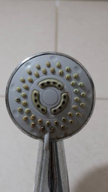 Banyodaki eski kirli duş başlığının resmi.
