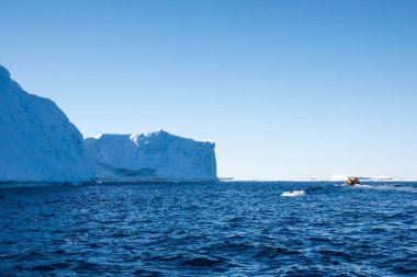 Tourists approaching large tabular iceberg on a zodiac boat, Weddell Sea, Antarctica clipart