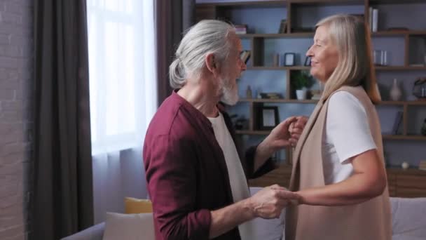 高齢者の幸せなカップルの自宅で踊り 白髪の夫と妻が踊る 幸せな高齢者の関係 中年祖父母が一緒に家でリラックス — ストック動画