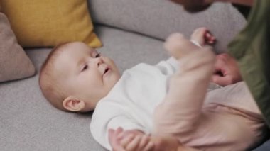 Dad plays with his little baby, on the couch in a cozy apartment. Fatherly love. Father hugs and kisses his little daughter.