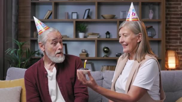 Boldog Ősz Hajú Pár Kúpos Sapkában Élvezik Születésnapi Ünnepséget Otthon — Stock videók