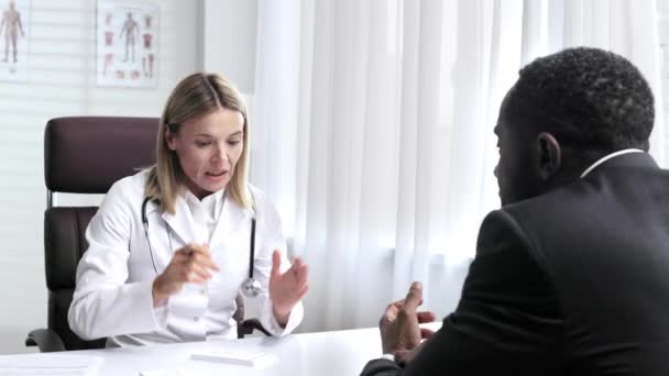 彼女のオフィスでアフリカ系アメリカ人男性患者の受信に怒っている医師の女性 薬の処方書を書く 医者の診察 医者は患者のストレス下にある — ストック動画