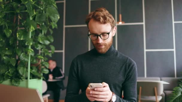 머리의 프로그래머나 안경을 사업가가 카페에 노트북을 스마트폰으로 메신저와 채팅을 편지를 — 비디오