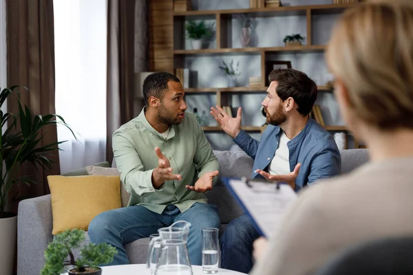 A family psychologist conducts a session in a beautiful office. LGBT couple at a psychotherapists appointment. Psychologist for gays. Support for the LGBT community in visiting a psychologist