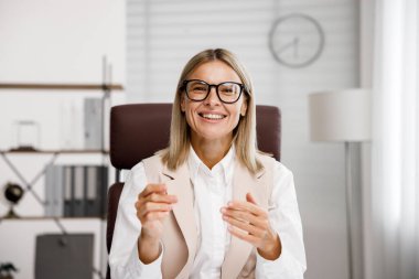 Smiling mid aged business woman looking at web cam video conference calling in virtual chat meeting, giving remote training webinar class working from home office. Headshot face portrait. Webcam view clipart