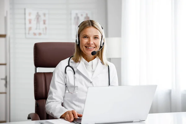 Telemedicine. Headshot portrait of smiling female doctor in headphones looking at camera. A female medical doctor remotely consults in a virtual online meeting with a patient. Online medicine.
