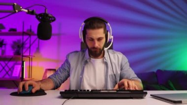 Cybersportsman in a neon room. Gamer bearded guy, in gaming headphones, challenges. Lifestyle gamer, online games. E Sports.
