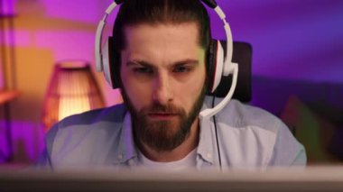 Close-up portrait of an esportsman. A professional gamer plays a computer video game, communicates in a headset with a team at the E-Sport championship. cyber gaming arena