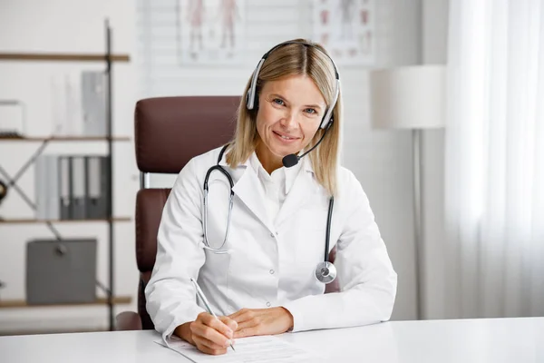 Telemedicine. Headshot portrait of smiling female doctor in headphones looking at camera. A female medical doctor remotely consults in a virtual online meeting with a patient. Online medicine.