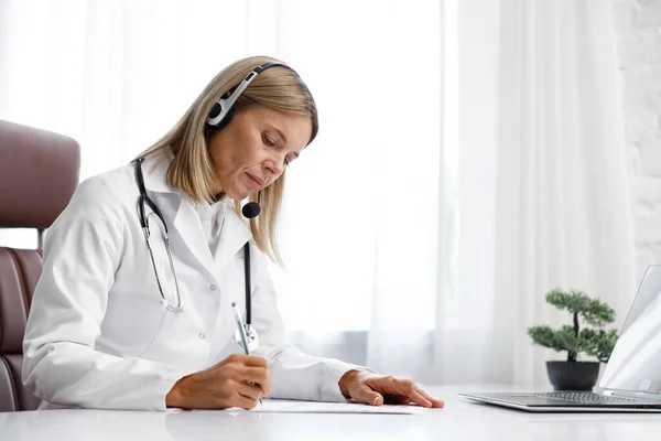 Telemedicine. Headshot portrait of smiling female doctor in headphones looking at camera. A female medical doctor remotely consults in a virtual online meeting with a patient. Online medicine.