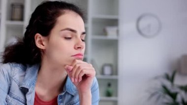 Young curly brunette sits stressed at the table feeling apathy and depression from overwork at work. Burnout from the modern world. Problems in life, bad news