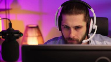 Close-up portrait of an esportsman. A professional gamer plays a computer video game, communicates in a headset with a team at the E-Sport championship. cyber gaming arena