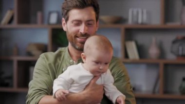 Close-up portrait of a father with a baby in his arms. Dad loves his little daughter, gently kisses. Father is on maternity leave. Paternity Leave. Paternal love.