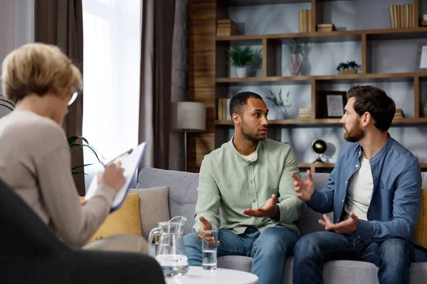 Family quarrel at the reception at the psychologist. LGBT couple at a psychotherapists appointment. Psychologist for gays. Support for the LGBT community in visiting a psychologist