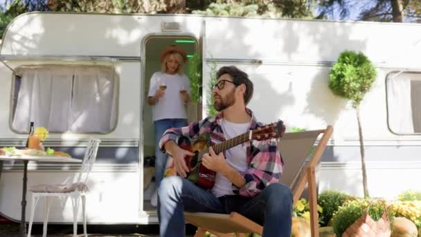 Guy Plays Guitar Front Travel Trailer Girl Offers Drink Rest — Stock Video