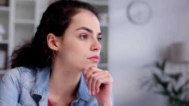 Young curly brunette sits stressed at the table feeling apathy and depression from overwork at work. Burnout from the modern world. Problems in life, bad news