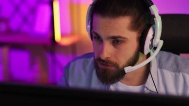 Close-up portrait of an esportsman. A professional gamer plays a computer video game, communicates in a headset with a team at the E-Sport championship. cyber gaming arena