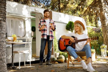Seyahat karavanının yanında piknik yapan sevimli genç bir çift. Sarışın kız gitar çalıyor ve adam şarap kadehleri getiriyor. Şehrin dışında dinlen.