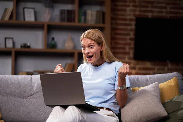 Dizüstü Bilgisayara Bakıp Başarıyı Kutlayan Evdeki Koltukta Oturan Heyecanlı Kadın — Stok fotoğraf