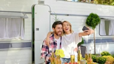 Karışık yarış arkadaşları cep telefonuyla selfie çekiyor, açık hava partileri seyahat karavanı arka planında. Şehrin dışında dinlen. Mutlu insanlar eğlenir. Yazın hafta sonları