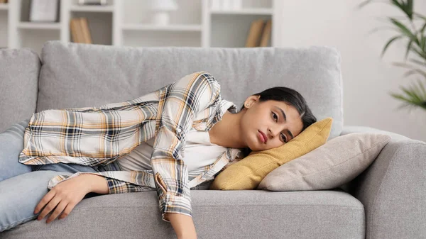 Yorgun Hintli kız kanepede kendini bitkin hissediyor. Depresyonda, motivasyon eksikliği, üzüntü, can sıkıntısı. Yorgunluktan, stresten kanepede yığılıp kalıyor. Söndür