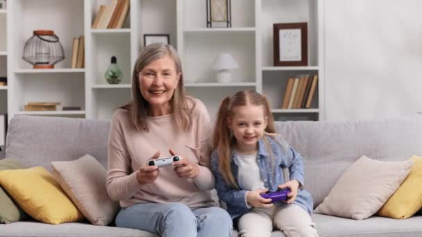60多岁的感情祖母和年幼的孙女在游戏平台上玩电子游戏 玩得很开心 老奶奶赢了比赛 为胜利而高兴 — 图库视频影像
