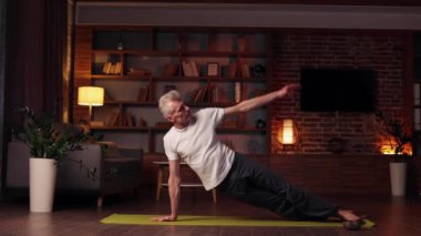 Yoga at home. The gray-haired man does yoga at home, doing asanas. Sports, stretching, gymnastics of an elderly man. Healthy lifestyle in old age