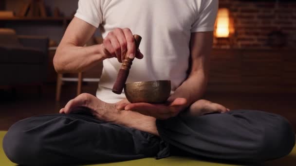 Пожилой Седой Мужчина Практикует Йогу Дома Используя Тибетскую Чашу Медитации — стоковое видео