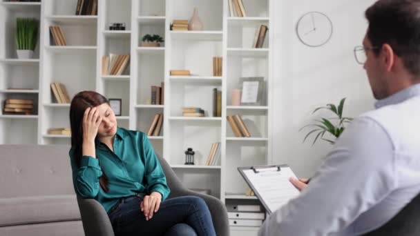一位专业的心理学家会咨询一位处于压力和抑郁状态的女性患者 她正坐在办公室的椅子上 他写在纸上 顾问心理学家的概念 — 图库视频影像
