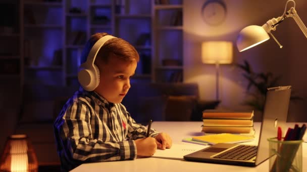 可爱的男生在耳机学习在线从家里 观看网络课程或听导师通过视频电话 电子学习流行病隔离 儿童的远程教育 — 图库视频影像