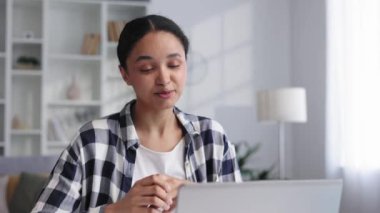 Çekici genç iş kadını evden çalışıyor, gülümsüyor, video görüşmesinde sohbet ediyor. Çekici Afrikalı Amerikalı kız öğrenci evden okuyor, uzaklardan öğreniyor, çalışmalarını sunuyor. Görüntüyü kapat