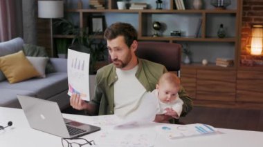 Father on maternity leave, holding an online conference, a meeting in the home office with a small child in his arms. Dad with a child. Freelancer combines child care and work. Paternity leave.