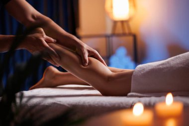 Erkek masörlerin elleri, kadın ziyaretçi bacağına baskı yapar, masaj salonlarında rahatlatır. Genç bir kadın için vücut bakımı. Yaralı bir bacak için tedavi yöntemi, sağlığın düzeltilmesi.