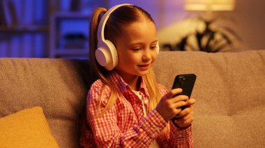 Akşamları beyaz kulaklıklı neşeli bir çocuk oturma odasındaki bir kanepede oturur, akıllı bir telefona tıklayarak. Küçük bir kız telefonda en sevdiği müziği seçer ve dans etmeye başlar.