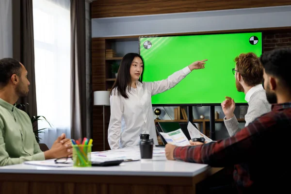 Marketing strategy analysis, stock market trading or corporate teamwork. A team of startups at a table with a large green screen TV. Mixed race business team