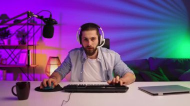 Gamer bearded guy, in a gaming headset, wins a video game. Cybersportsman in a neon room. Lifestyle gamer, online games. Victory in the E-Sport tournament.