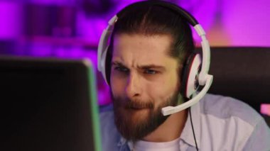 Close-up portrait of an esportsman. A professional gamer plays a computer video game, communicates in a headset with a team at the E-Sport championship. cyber gaming arena
