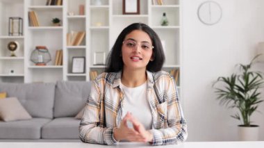Hintli bir kız öğrenci üniversitede online bir derste bir web sitesi dinliyor. Güzel genç bir kadın, bir video konuşmasında gülümsüyor. Karantinada çalışmak, podcast dinlemek, kamera görüntüsü