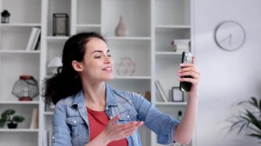 Masada oturan genç kıvırcık esmer bir cep telefonu kullanıyor. Bir vidoe akıllı telefonunuzla anında haberleşir. Çevrimiçi iletişim, insan hayatında akıllı telefon.