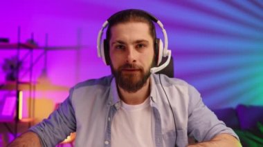 Cybersportsman in a neon room. Nervous Gamer bearded guy, in gaming headphones, is defeated in a video game. Lifestyle gamer, online games. Defeat in the E-Sports Tournament.