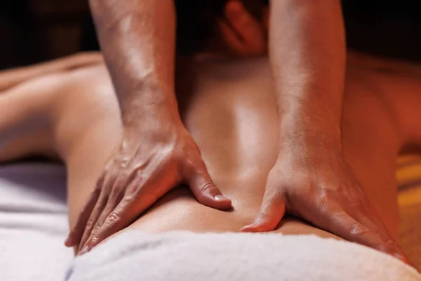 Extreme closeup of masseurs male hands gently pressing hands along clients back. Concept of aesthetic relaxing massage in spa salon, recovery, reboot