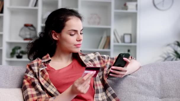Sorrindo Muito Jovem Morena Segurando Telefone Celular Cartão Crédito Sentado — Vídeo de Stock