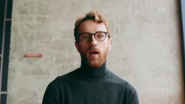 Genç, kızıl saçlı bir adam, şık bir kafede. Vlog kaydı, çevrimiçi video konferansı, video görüşmesi, çevrimiçi öğrenme, dersler, konferans. Röportaj, online eğitim. Web kamerasından görüntüle