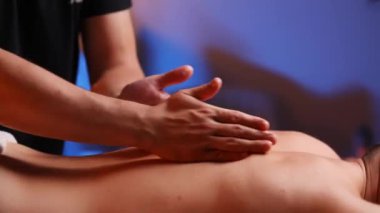 Erkek masörün elleri ziyaretçilerin sırtını ovuyor. Yorgun kaslar için tedavi edici bir masaj. Spa merkezinde puan masajı. Sağlıklı bir yaşam tarzı için vücut terapisi
