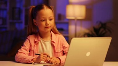 Masada oturan sevimli kız öğrenci evde online ders çalışıyor, web dersi izliyor ya da video aracılığıyla özel ders dinliyor, salgın izolasyonundan faydalanıyor. Çocukların uzaktan eğitimi