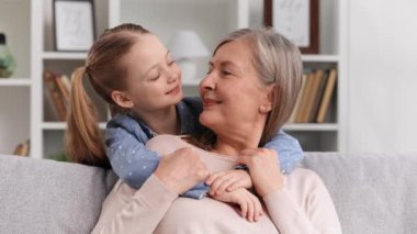 Küçük bir torun 60 yaşındaki büyükannesine sarılıyor, sevgisini gösteriyor. Aile sevgisi, uzun zamandır beklenen bir buluşma, nesillerin bağlantısı.
