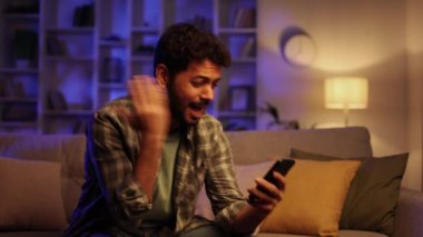 Kanepede oturan endişeli genç Arap çocuk telefonuna bakıyor ve neden çalışmadığını anlamıyor. Kızgın öğrenci gördüğü kötü habere inanmıyor.