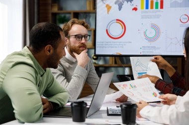 A team of young mixed race businessmen working on a startup. Business strategy, teamwork. Discussion and generation of ideas. Communication network. multinational professional team