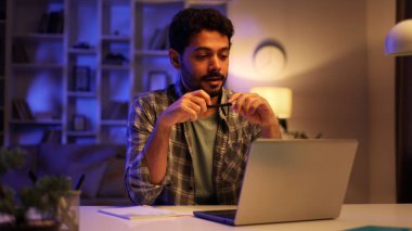 Sakallı, konsantre olmuş erkek Arap işadamı akşamları oturma odasında dizüstü bilgisayar başında ders çalışıyor. Genç bir adam video konferansını dikkatle dinliyor ve bilgileri not defterine yazıyor.