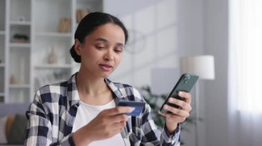 Masada otururken elinde cep telefonu ve kredi kartıyla gülümseyen Afro-Amerikan esmer bir kız. Cep telefonu ödemesini kullanarak internetten alışveriş yapan mutlu bir kadın. Elektronik bankacılık uygulaması